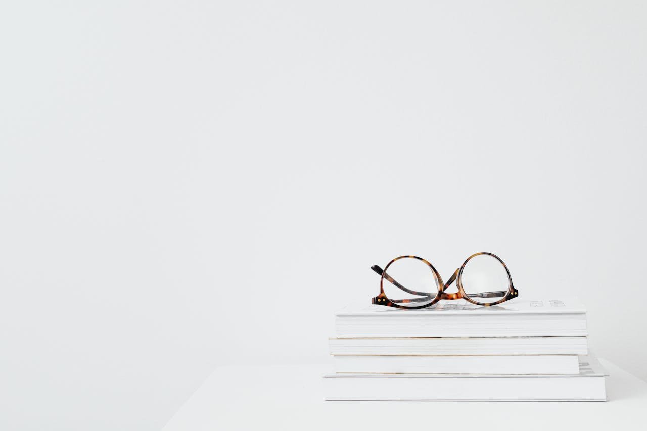 Black Framed Eyeglasses on Stack of Books